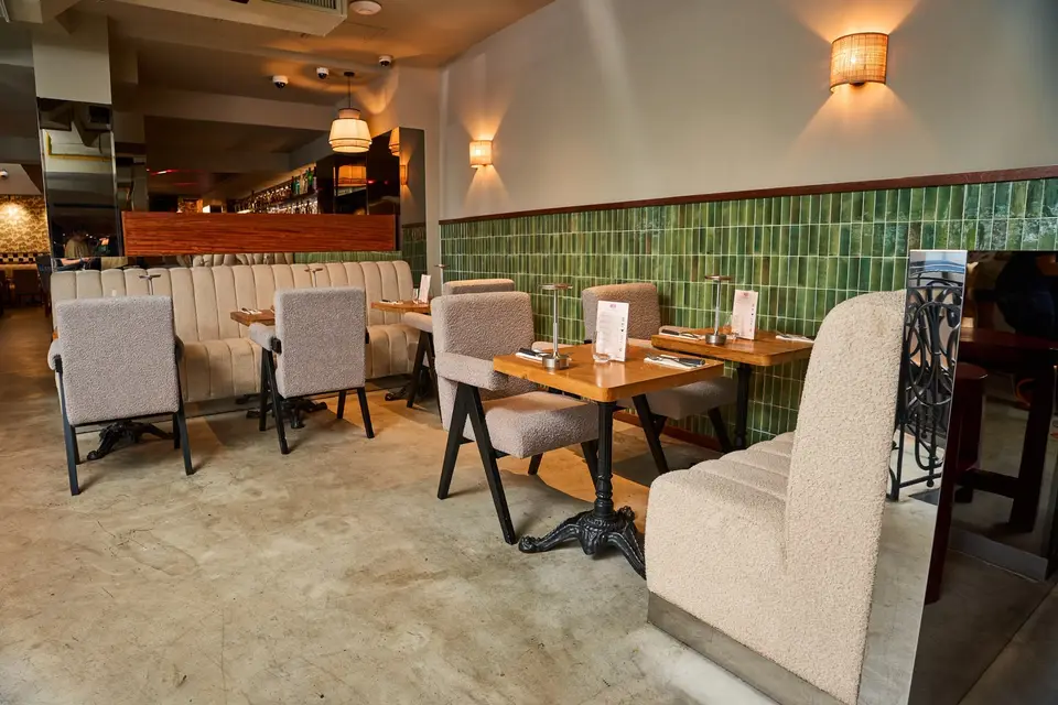 Coin repas avec mur en carreaux de céramique verte et fauteuils en bouclette