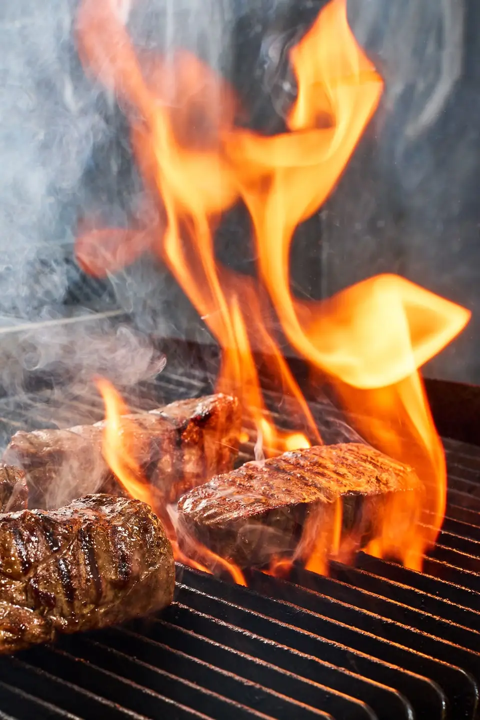 Pièces de bœuf sur le grill léchées par de hautes flammes